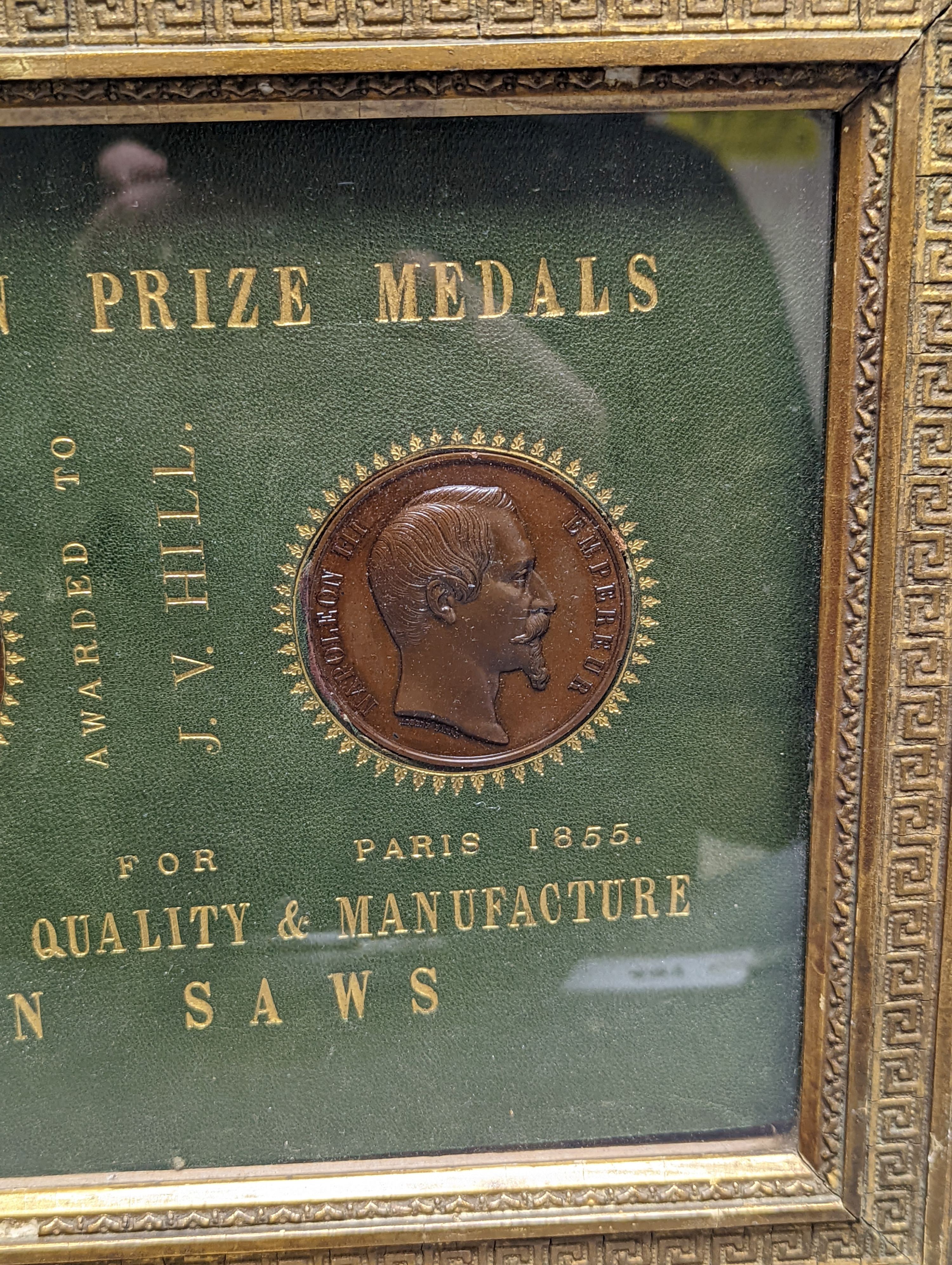 Two Exhibition Prize Medals, to JV Hill, saw manufacturers, London 1851 and Paris 1855, frame 34cm. wide, and a collection of Victorian coin tokens, in Pinches & Co. case, 1857